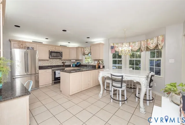 a kitchen with granite countertop white cabinets stainless steel appliances a sink and a window