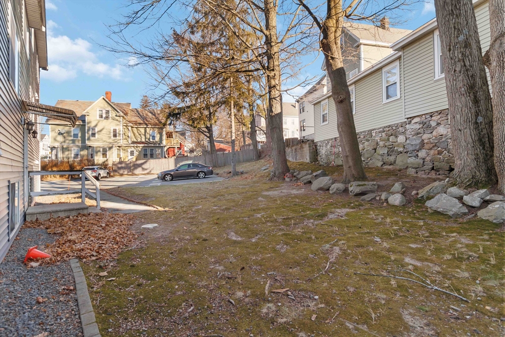 1 19th Street, Unit 3 Lowell, MA 01850 - Photo 20 of 22 a backyard of a house with large trees and parked