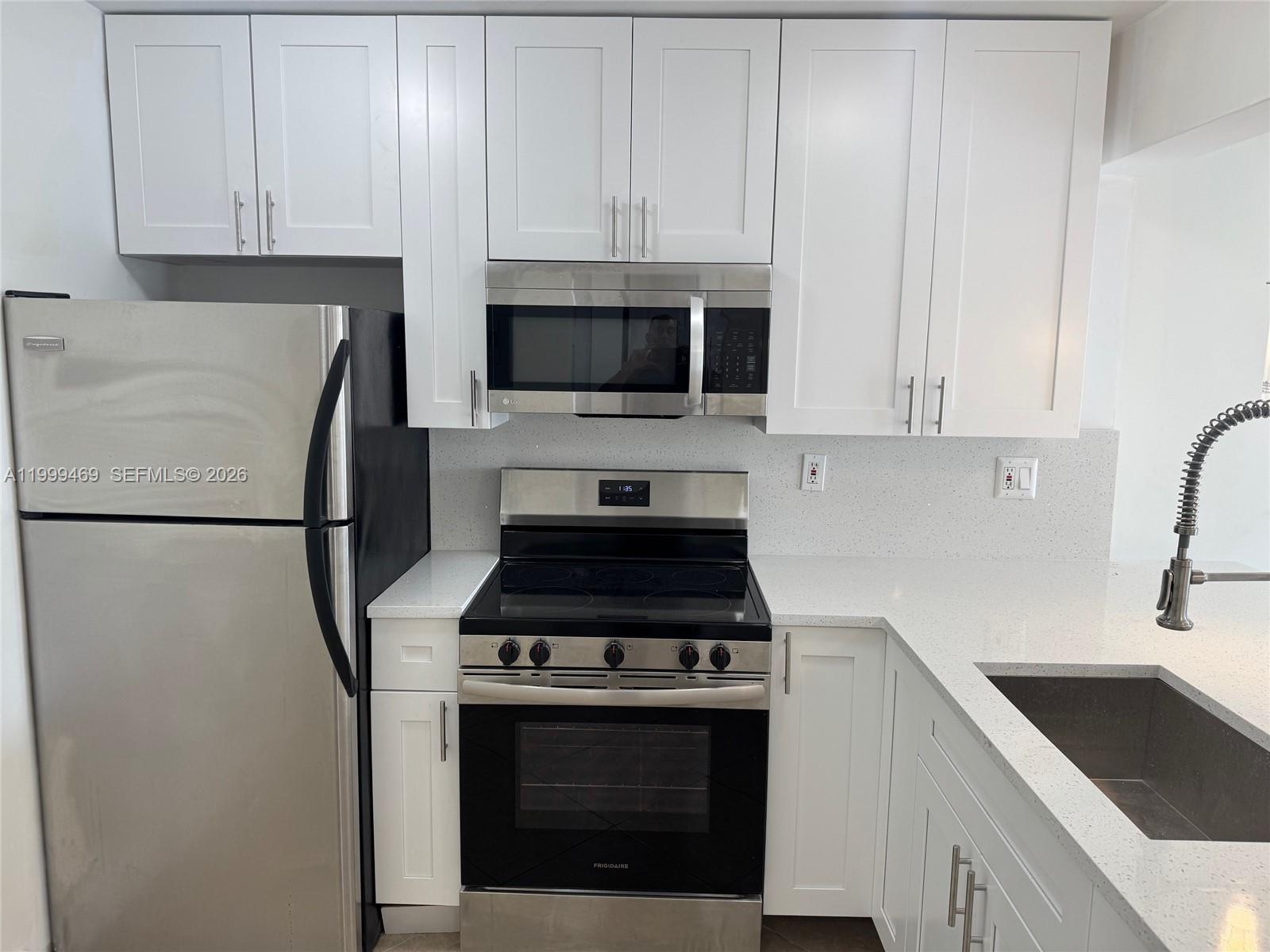 492 Northwest 165th Street, Unit C309 Miami, FL 33169 - Photo 4 of 15 a kitchen with stainless steel appliances granite countertop white cabinets a stove top oven a sink and dishwasher