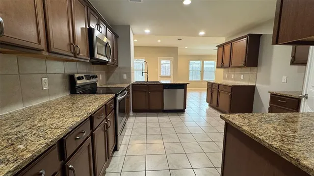 a kitchen with stainless steel appliances granite countertop a stove a sink and a microwave