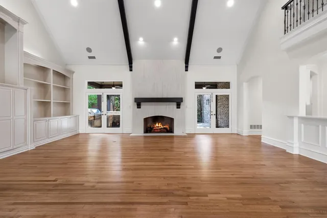 a view of an empty room with wooden floor fireplace and a window