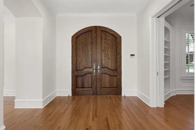 an empty room with wooden floor and entrance