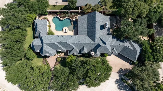 an aerial view of a house with a yard and trees all around