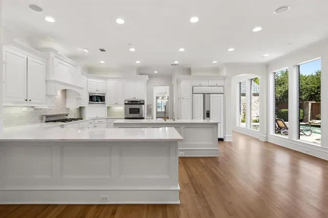 a large white kitchen with large windows and white cabinets