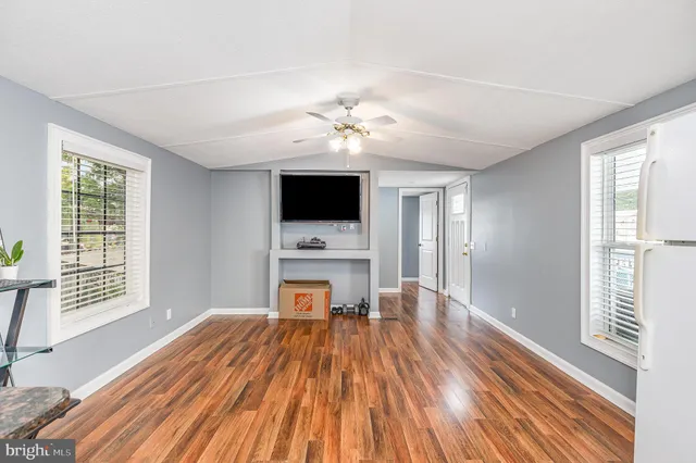 a view of a livingroom with a fireplace a ceiling fan and wooden floor