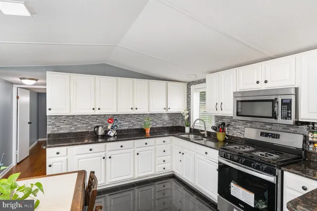 a kitchen with granite countertop white cabinets and stainless steel appliances