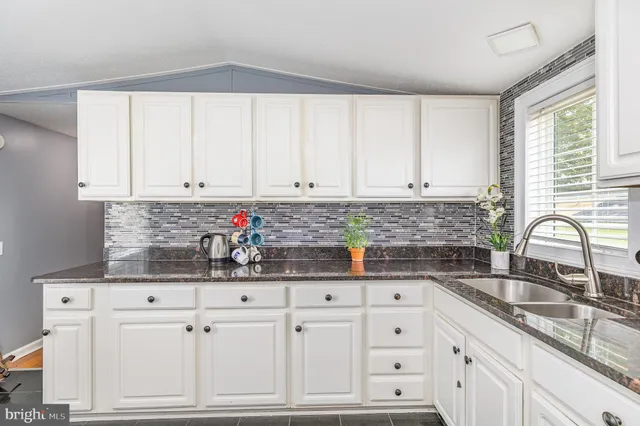a kitchen with stainless steel appliances granite countertop a sink window and cabinets