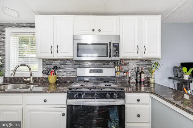a kitchen with granite countertop white cabinets and appliances
