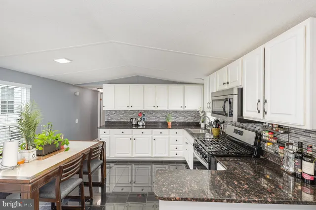 a kitchen with granite countertop a stove a sink and a refrigerator
