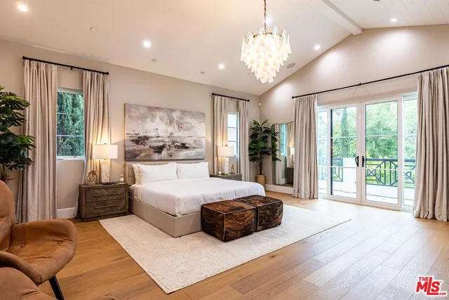 a bedroom with a bed chandelier and a window