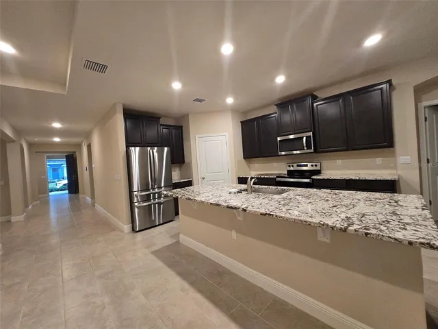 a large kitchen with a large counter top stainless steel appliances and cabinets
