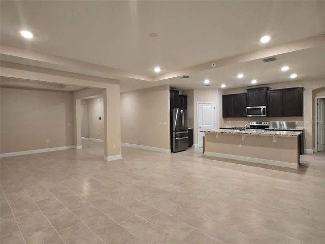 a view of kitchen with stainless steel appliances kitchen island granite countertop a stove and a refrigerator with white cabinets