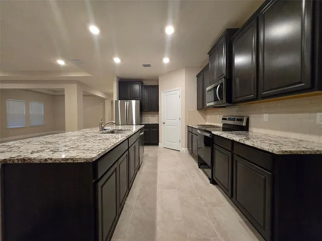 a kitchen with granite countertop kitchen island stainless steel appliances sink stove microwave and cabinets