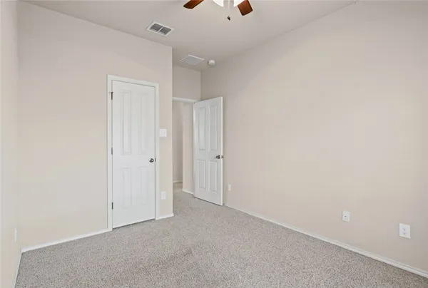 an empty room with a shower and a ceiling fan