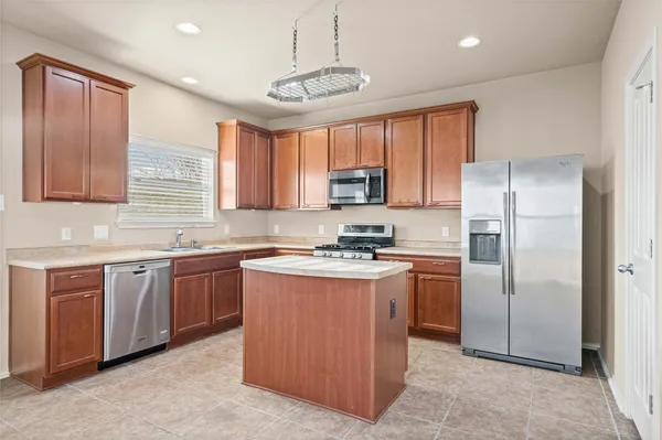 a kitchen with stainless steel appliances granite countertop a stove top oven a refrigerator and a sink with cabinets