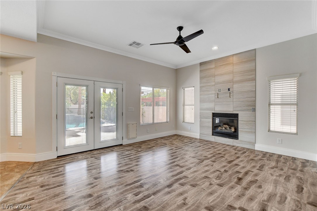 191 Verde Ridge Court Henderson, NV 89012 - Photo 11 of 36 Unfurnished living room featuring wood finished floors, crown molding, baseboards, ceiling fan, and a fireplace