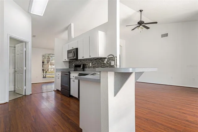 a kitchen with a refrigerator a stove top oven a wooden floor and cabinets