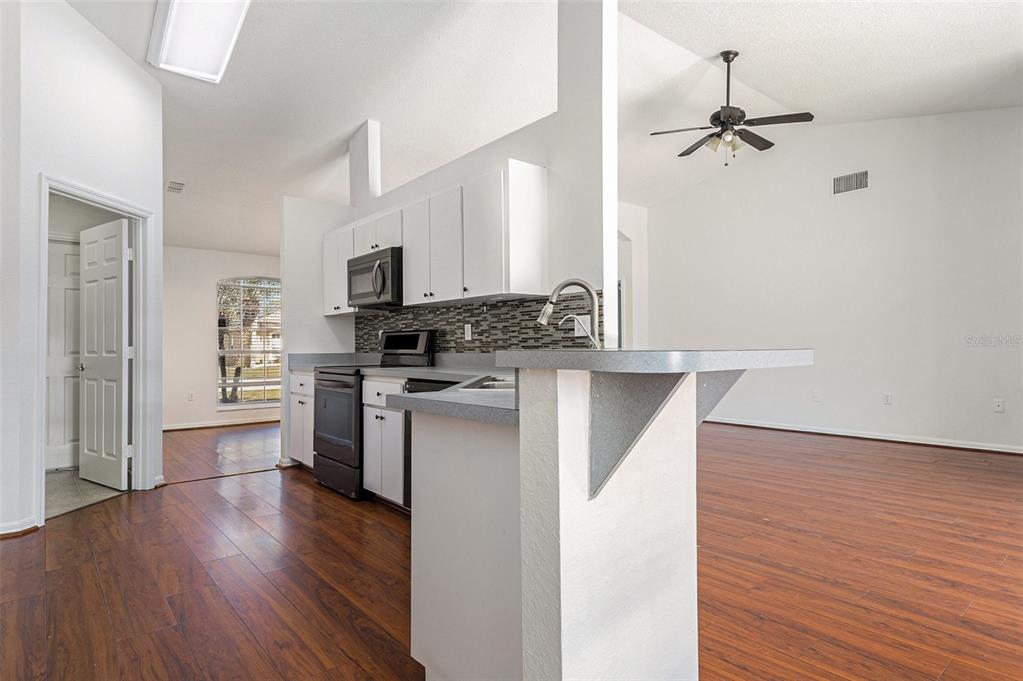 7182 Summit Drive Winter Haven, FL 33884 - Photo 23 of 27 a kitchen with a refrigerator a stove top oven a wooden floor and cabinets