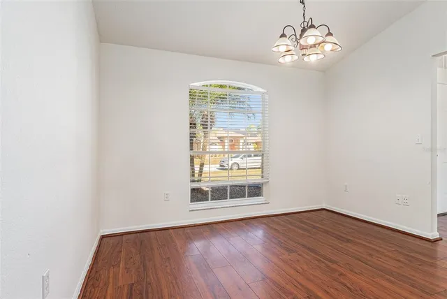 a view of empty room with wooden floor and window