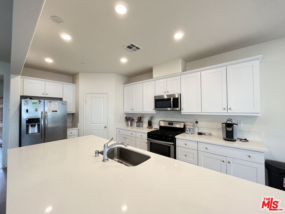 11785 Connell Road Riverside, CA 92505 - Photo 5 of 39 a kitchen with stainless steel appliances kitchen island granite countertop a sink dishwasher a refrigerator and white cabinets with wooden floor