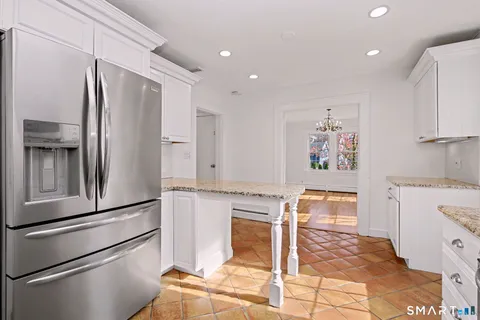 a living room with stainless steel appliances furniture a refrigerator and a kitchen island