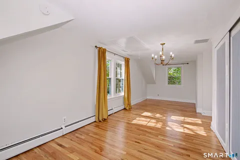an empty room with wooden floor chandelier and windows