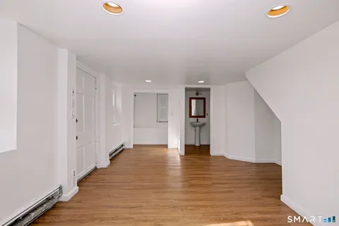 a view of an empty room with wooden floor and staircase