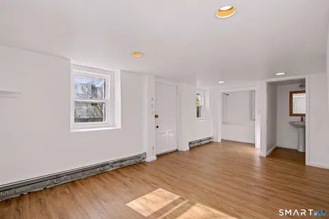 a view of an empty room with window and wooden floor