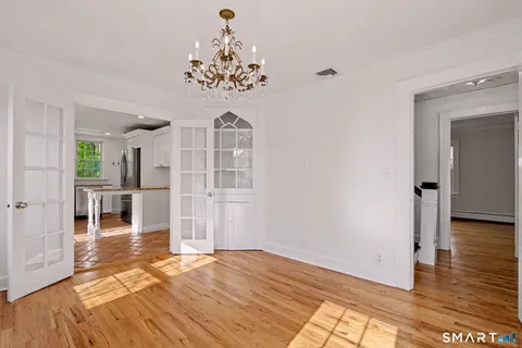 a view of a room with wooden floor chandelier and windows