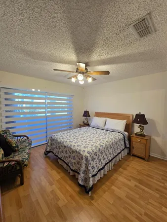 a bedroom with a bed and dresser with wooden floor