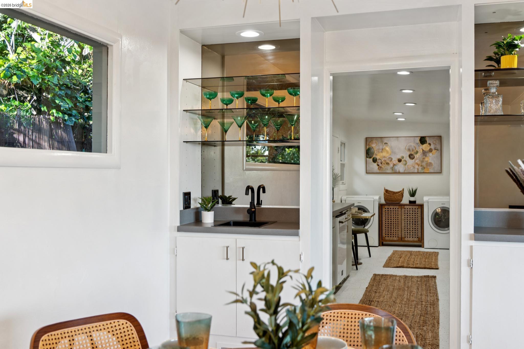 2301 Oak Street Berkeley, CA 94708 - Photo 6 of 61 Built-in wet bar with glass shelving, integrated sink, and dark-finish faucet