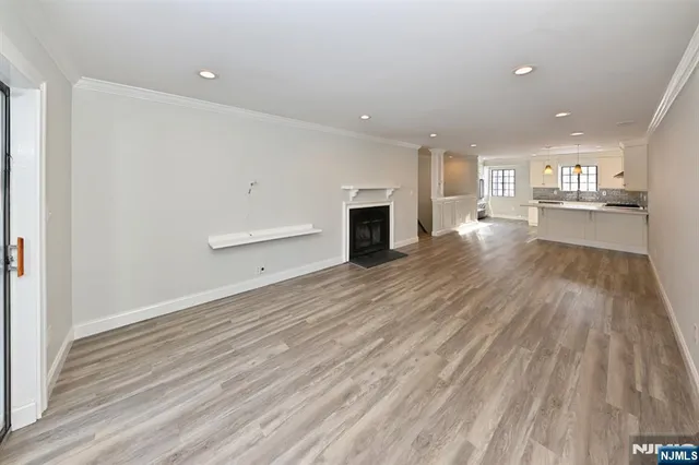 an empty room with wooden floor fireplace and windows