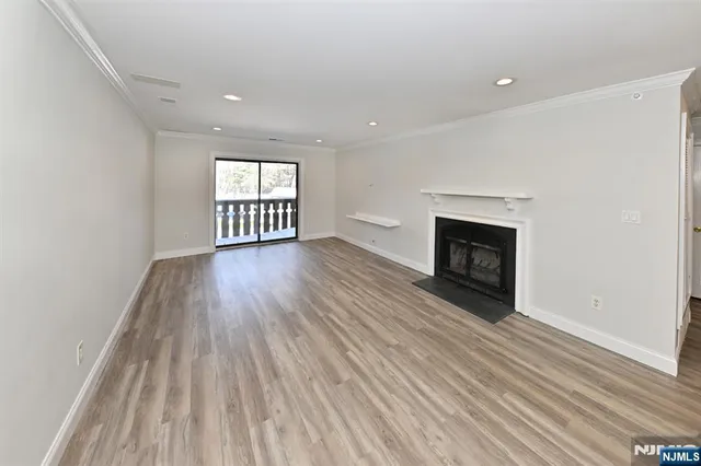 an empty room with wooden floor fireplace and windows