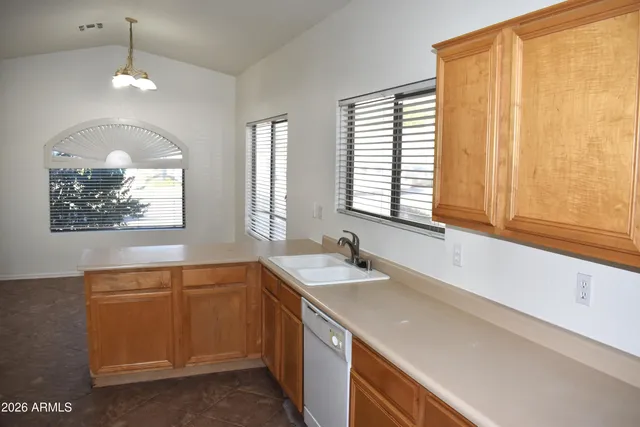 an empty room with wooden floor cabinet and windows
