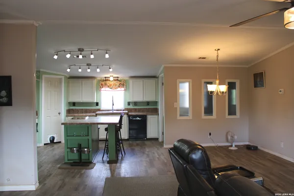 a kitchen with a refrigerator a sink dishwasher a dining table and chairs with wooden floor
