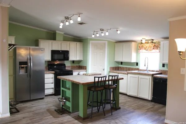 a kitchen with kitchen island granite countertop a sink cabinets and stainless steel appliances