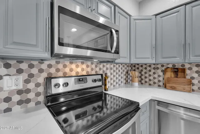 a view of kitchen with stainless steel appliances granite countertop a stove top oven a sink and a refrigerator