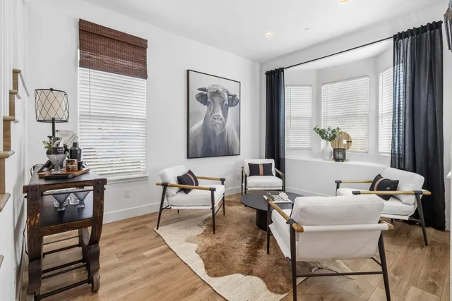 a living room with furniture a large window and wooden floor