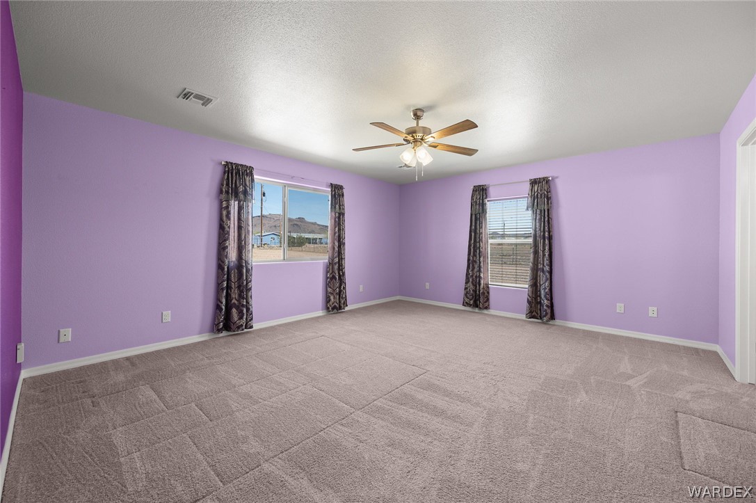 3411 West Carmichael Road Golden Valley, AZ 86413 - Photo 23 of 97 Empty room with a ceiling fan, light carpet, and a textured ceiling