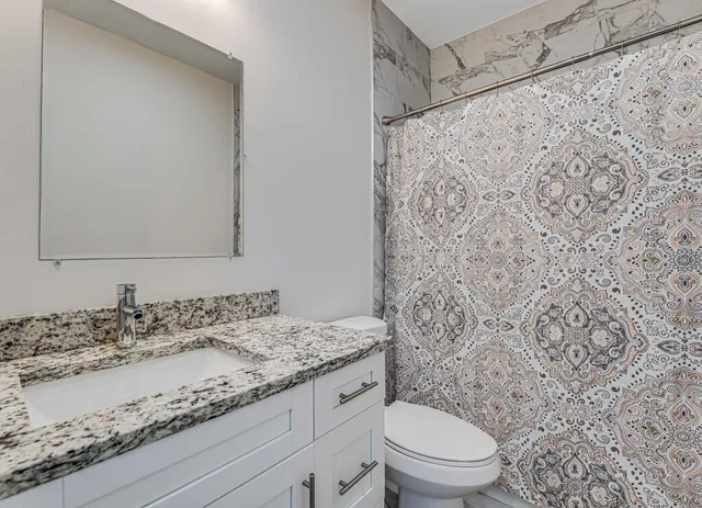 a bathroom with a granite countertop sink toilet and shower