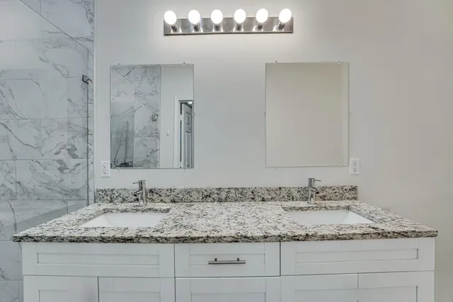 a bathroom with a granite countertop sink and a mirror