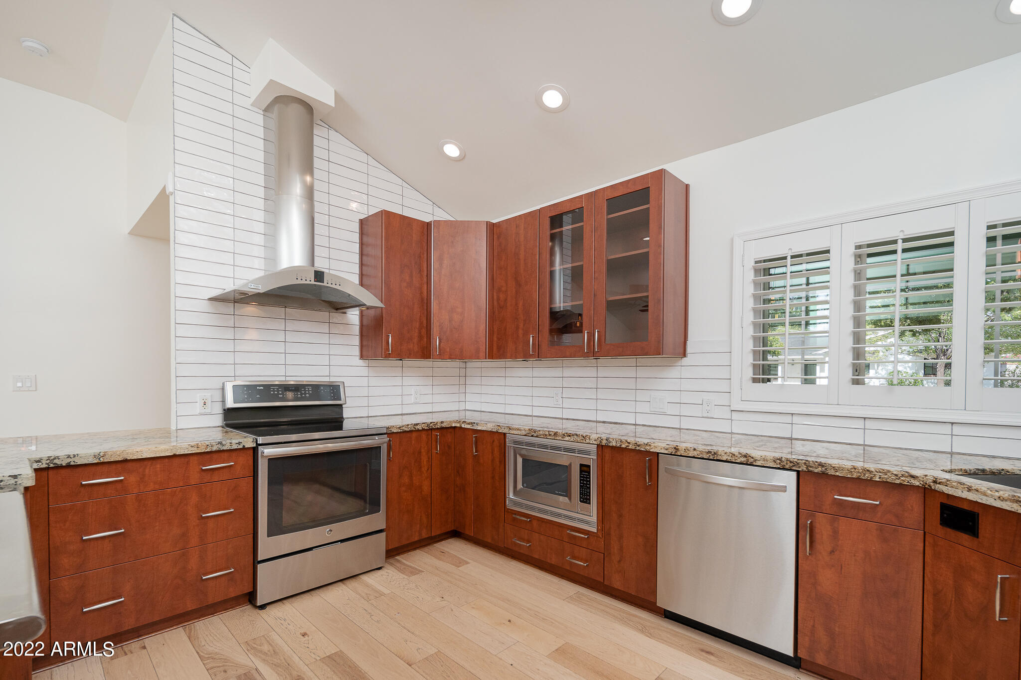 3864 North 50th Street Phoenix, AZ 85018 - Photo 14 of 15 a kitchen with stainless steel appliances granite countertop wooden cabinets a sink and a stove