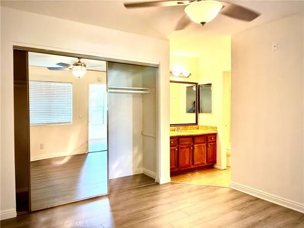 a view of a hallway with wooden floor and a bathroom