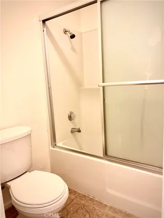 a white toilet sitting next to a bath tub and a shower