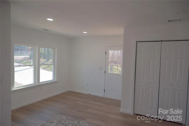 an empty room with wooden floor and windows