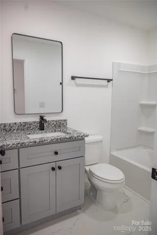 a bathroom with a granite countertop toilet sink and mirror