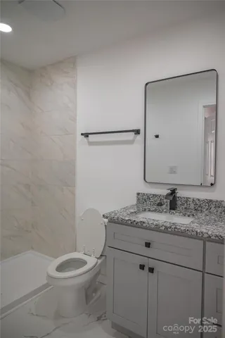 a bathroom with a granite countertop sink a toilet and a mirror