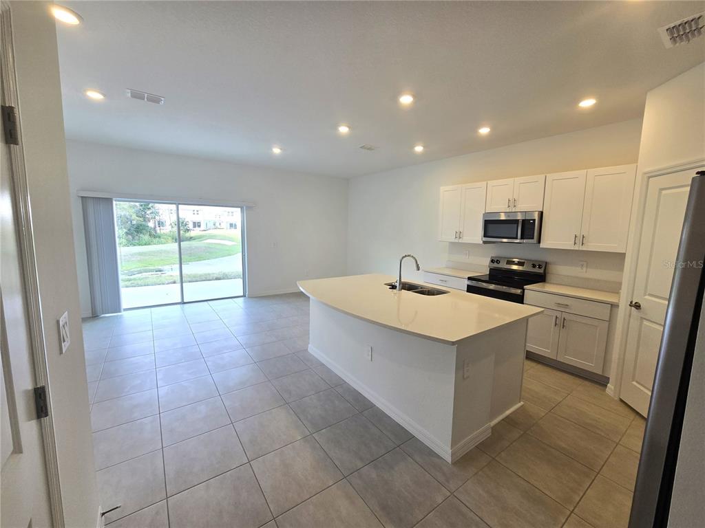 3575 Mayfair Street Kissimmee, FL 34758 - Photo 5 of 34 a kitchen with stainless steel appliances a stove a sink and a refrigerator
