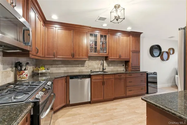 a kitchen with granite countertop a sink a stove and wooden cabinets