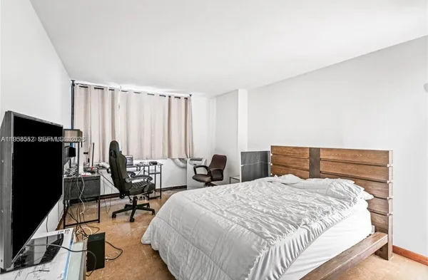 a bedroom with a bed a chair and a flat screen tv